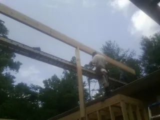 Carpenter setting a ridge beam over a new addition frame — Ice Dam Removal by Roofing Brothers in Mcminnville