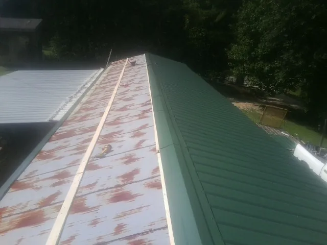Old rusted panels beside newly installed green metal roofing — Wind Damage Roof Repair by Roofing Brothers in Mcminnville