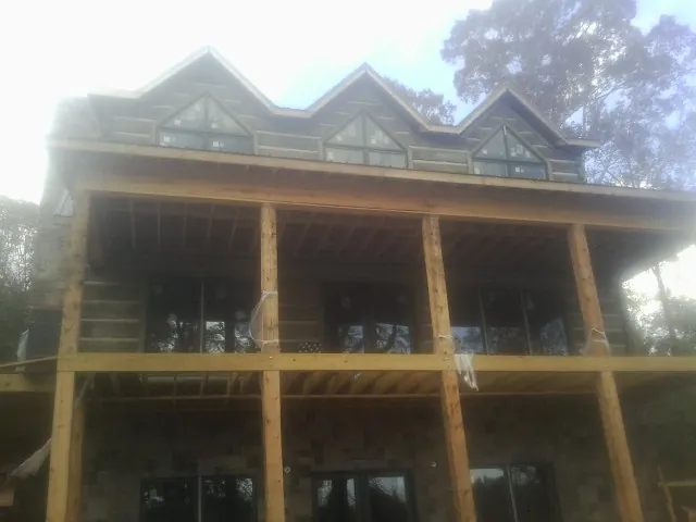 Dormers and porch framing on a large log home under construction — Roof Coating work by our crew in Mcminnville
