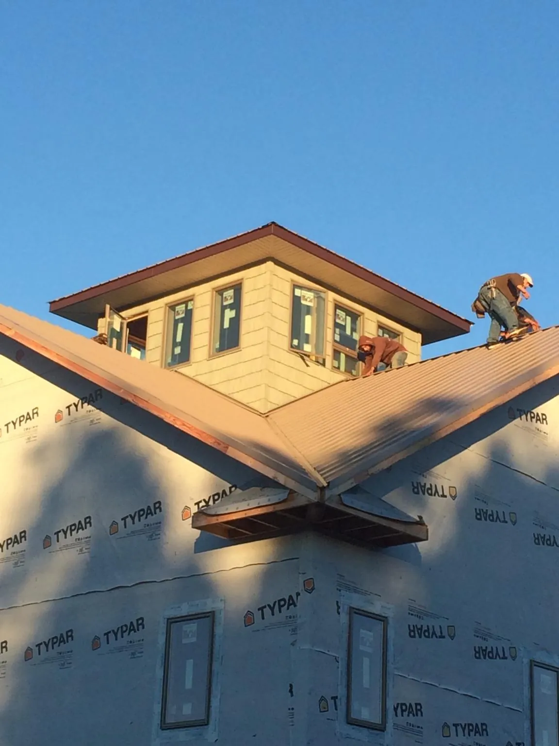 Roofers working around a rooftop cupola on a new metal roof at sunset — Roof Waterproofing in Mcminnville by Roofing Brothers